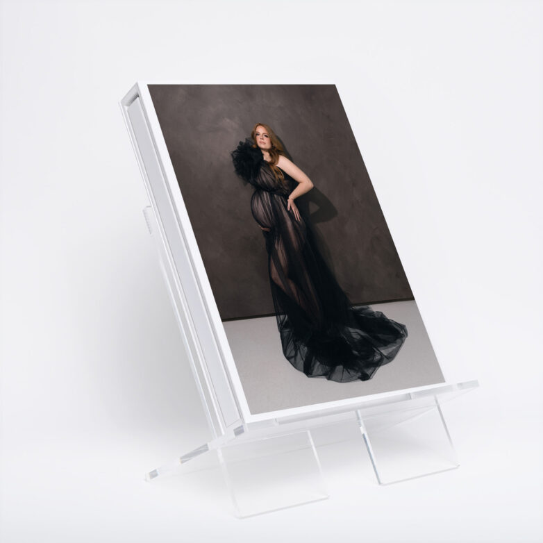 Luxury portrait album displayed on an acrylic stand featuring a fine art maternity photograph